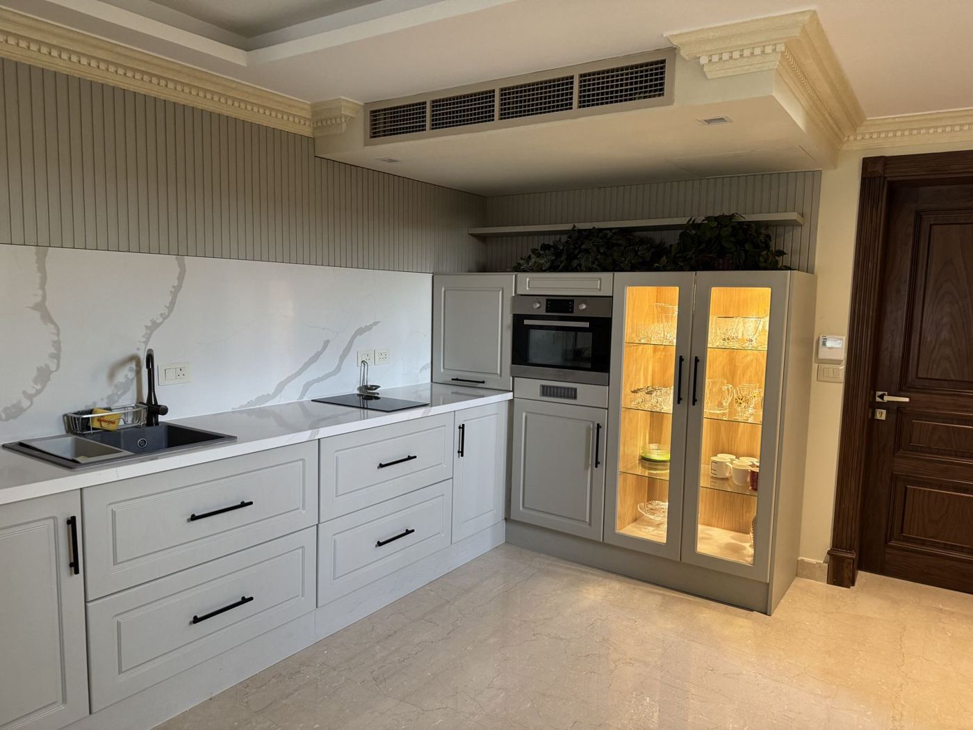 Classic grey kitchen with lit glass cabinet and marble splashback