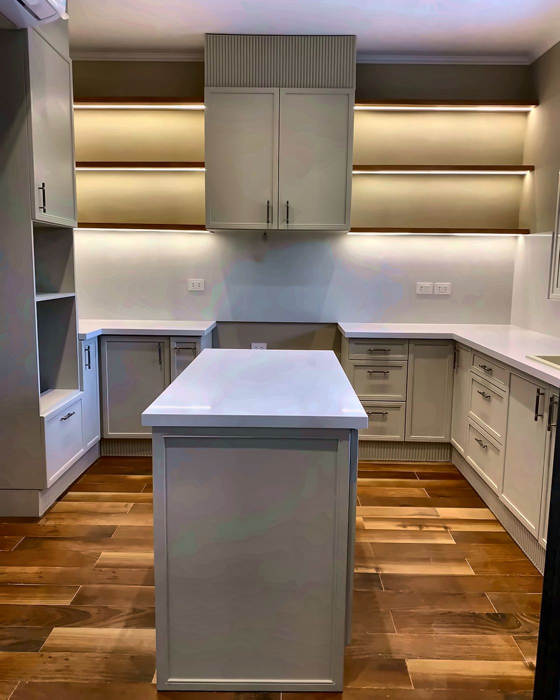 Sage grey kitchen with white island and lit open shelves, New Giza